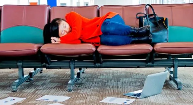 Traveller napping on an airport couch.